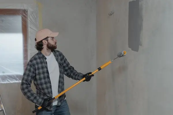 Painter rolling grey paint onto an interior wall in New Haven