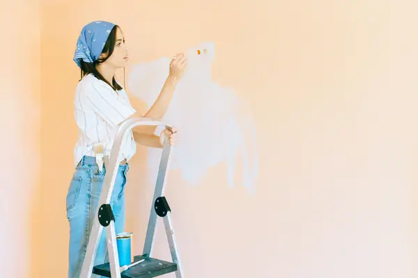Interior painting in New Haven: painter on a stepladder rolling a wall
